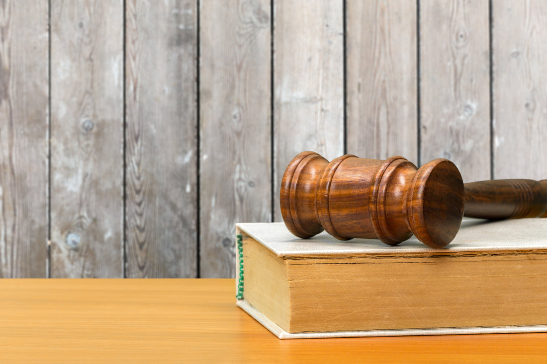 Mazo y libros de leyes sobre una mesa de madera, representando el marco legal de la oferta de empleo público del TAI