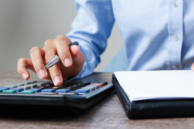 Persona usando una calculadora para calcular el sueldo neto de un funcionario TAI tras los descuentos de IRPF
