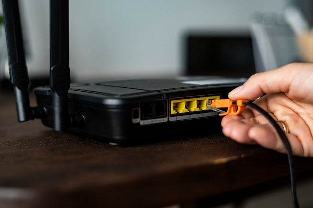 Persona conectando un cable de red a un router