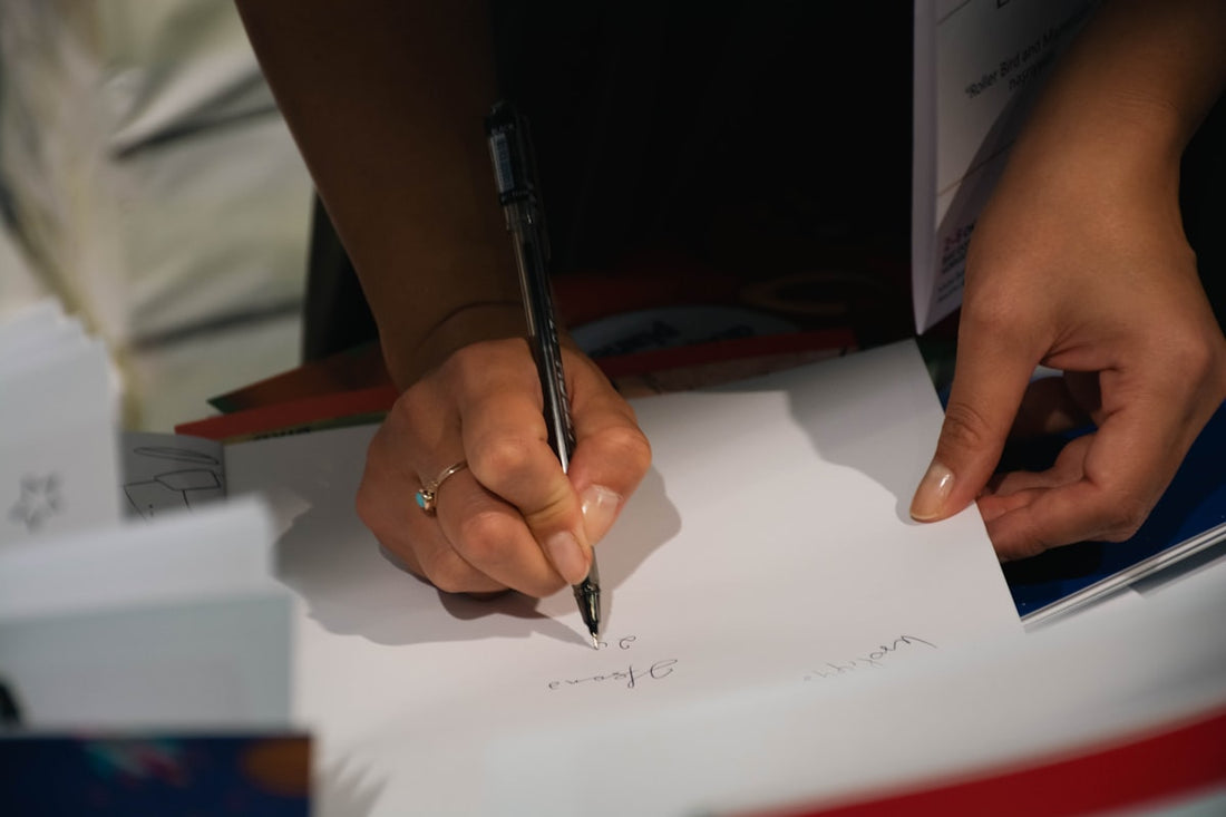 Persona escribiendo a mano sobre un papel con un bolígrafo