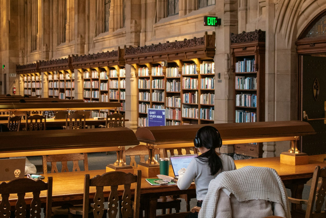 Persona estudiando en una biblioteca, preparando de nuevo el examen del TAI para una nueva convocatoria