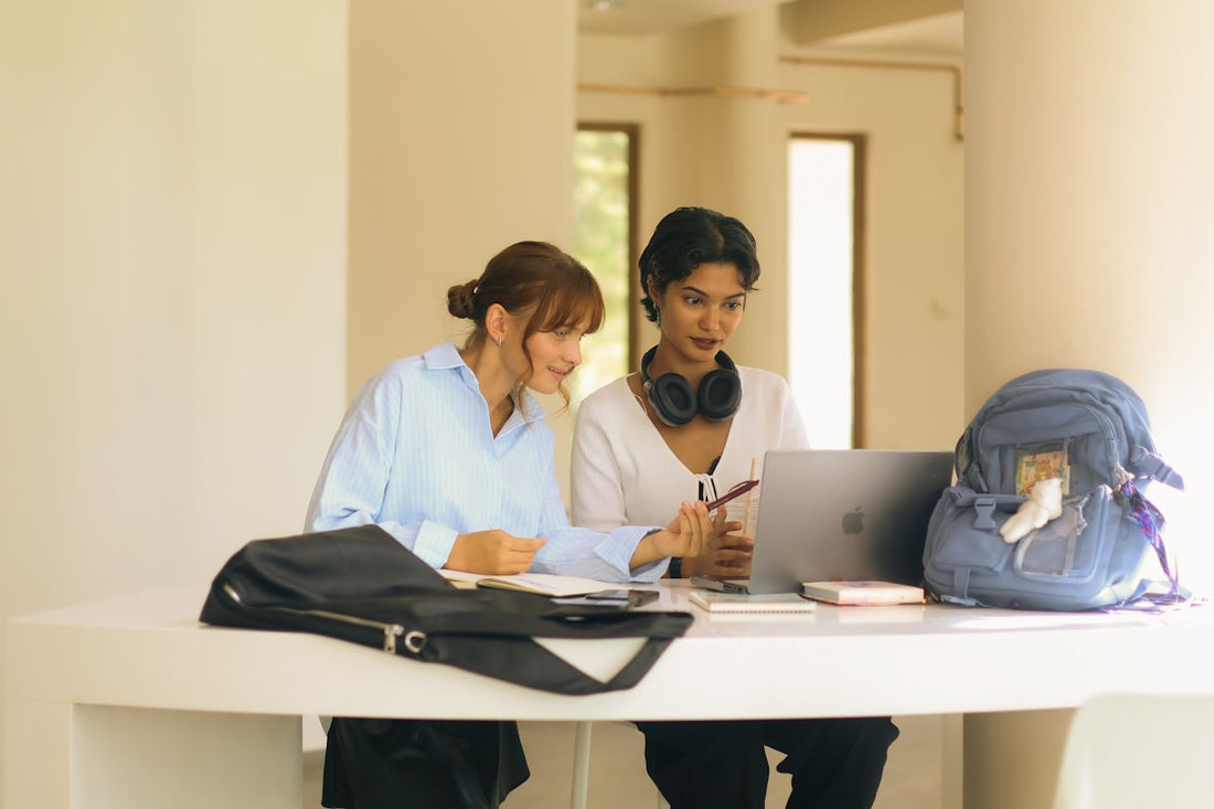 Dos personas estudiando juntas en una mesa con un portátil