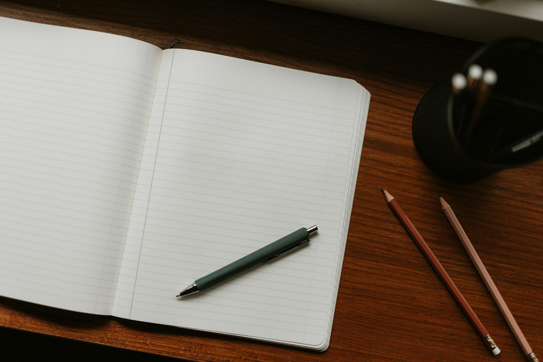 Cuaderno abierto con boli sobre un escritorio de madera, representando la elaboración de apuntes propios para el TAI