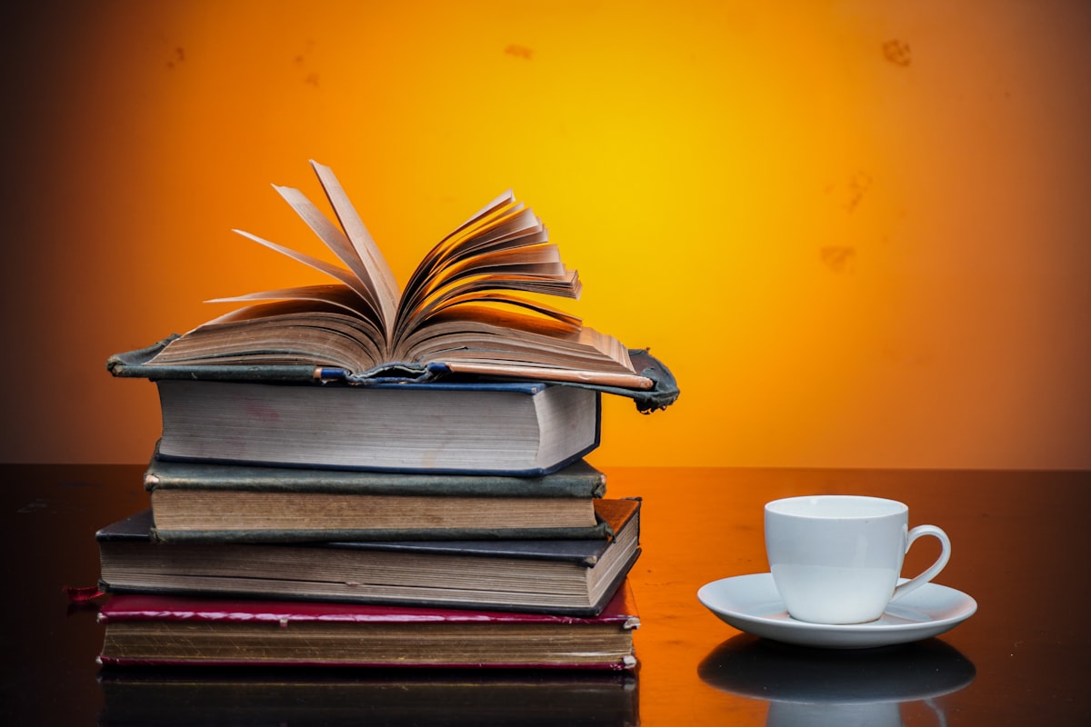 Pila de libros de estudio junto a una taza de café sobre una mesa, ambiente de repaso para el examen TAI