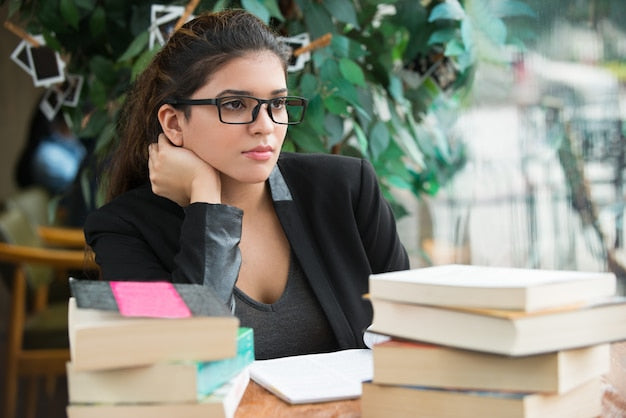 Persona pensativa rodeada de libros valorando cambiar de carrera hacia la oposición TAI