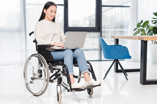 Mujer sonriente en silla de ruedas trabajando con un ordenador portátil