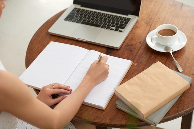 Persona escribiendo en un cuaderno junto a un portátil, representando el diario de preparación del TAI