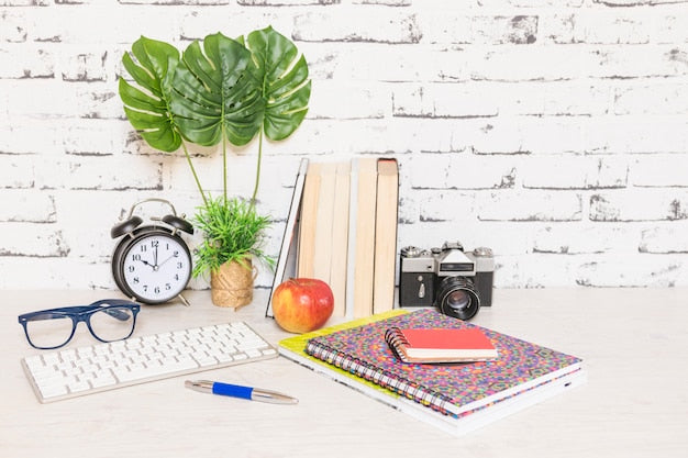Escritorio de estudio con teclado, libretas y libros, comparando estudiar en papel o en digital para el TAI