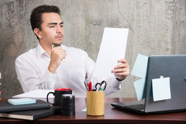 Persona revisando papeles de trabajo en un escritorio, valorando si pedir una excedencia para opositar al TAI