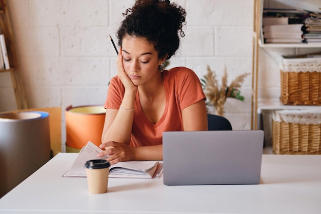 Persona estudiando en casa con un café y un portátil, reflexionando durante una sesión de preparación del TAI